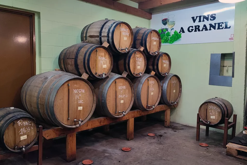 Barrils de fusta amb vi negre, blanc i rosat a la secció de vins a granel.