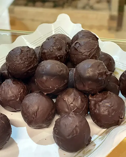 Safata amb bombons rodons coberts de xocolata negra, elaborats artesanalment.