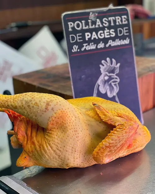 Pollastre de pagès exposat a la carnisseria Verntallat, amb cartell indicant l’origen local de St. Feliu de Pallerols.
