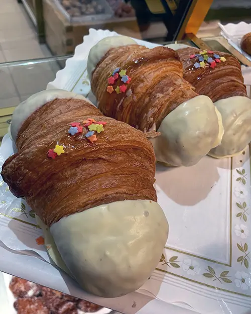 Croissants artesans coberts de xocolata blanca i decorats amb estrelletes de colors.