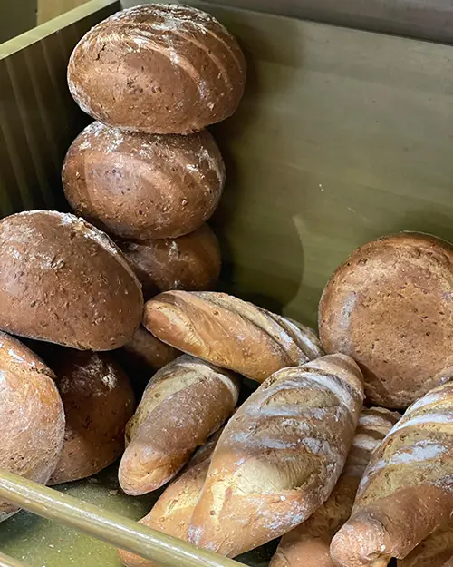 Assortiment de pans integrals i barres acabats de fornejar dins d’una caixa de fusta.