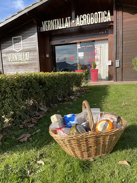 Exterior de l’Agrobotiga Verntallat amb un cistell ple de productes locals sobre la gespa.