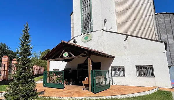 Entrada principal de l’Agrobotiga Verntallat d’Olot amb porxo, rètol i jardí exterior.
