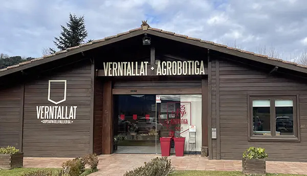 Vista frontal de l’edifici de l’Agrobotiga Verntallat amb rètol exterior i jardí.