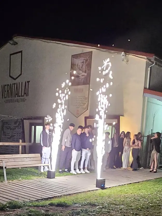 Entrada de la Sala Verntallat durant una celebració nocturna amb joves i efectes de foc fred.