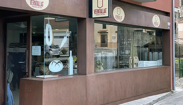 Vista exterior de l’Agrobotiga Verntallat a Sant Feliu de Pallerols amb aparador i rètols de la cooperativa.